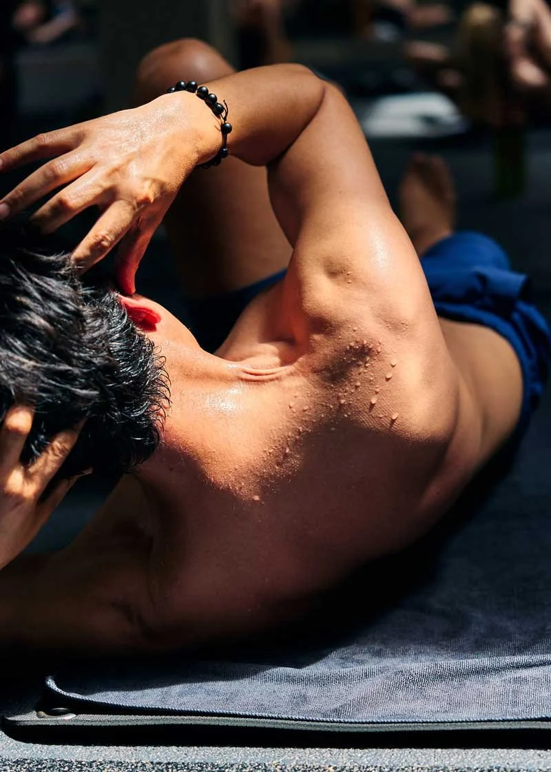 Shirtless, sweating man doing crunches on a yoga mat