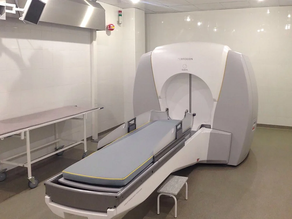 Photo of a treatment room with a large white radiosurgery machine and treatment table.