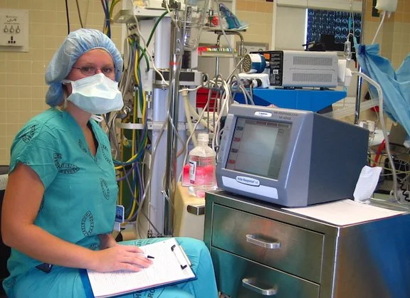 Photo of a staff member in theatre clothing next to a monitoring device in the operating theatre.