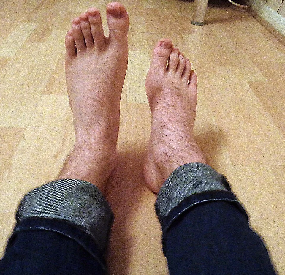 Photo of two feet; the right foot hangs down while the left is lifted.