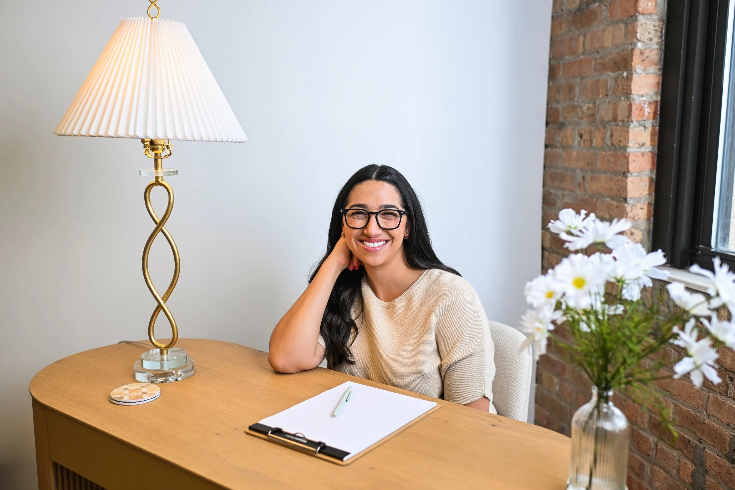 Sydney smiling sitting at her desk at the west loop office