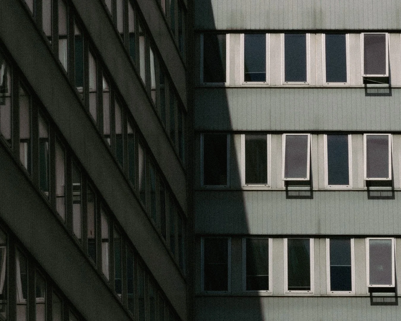 Close-up of the facades of two high-rise buildings, showing windows and the shadow cast by one building on the other.