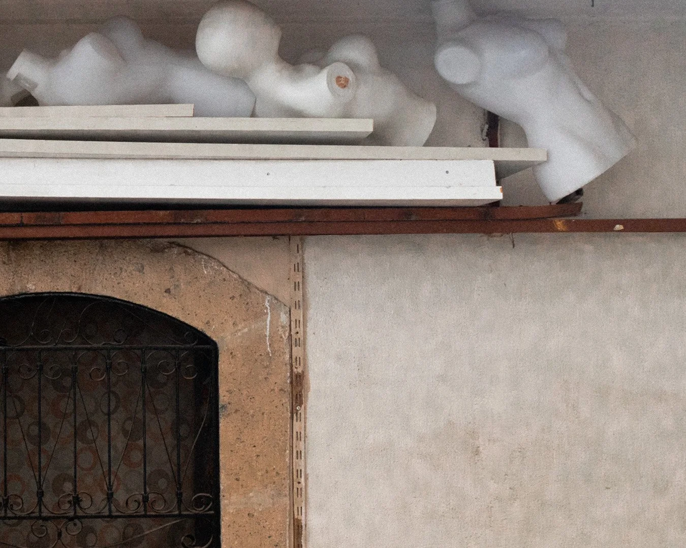 Store shelf with foam busts, white wooden panels, and a metal grate in front of a stone fireplace.