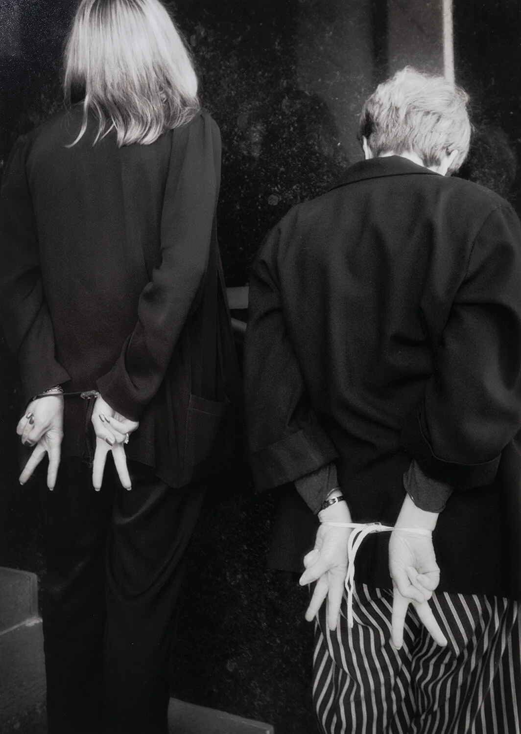 Arrested peace activists await transport to city jail after attempting to blockade the entrance to the Federal Building in Sacramento, March 2003. In an act of continuing witness, they flash the peace symbol with their cuffed hands to supporters behi