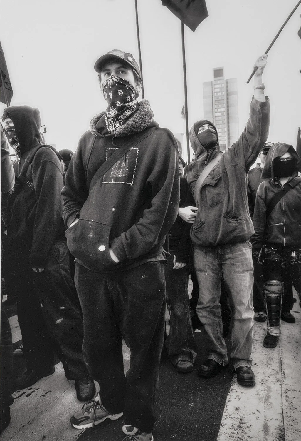 A group of anarchists prepare to march in San Francisco, January 2003. Standing tall in sneakers and sweatshirts, their faces are covered against the police security cameras filming from the tops of buildings nearby.