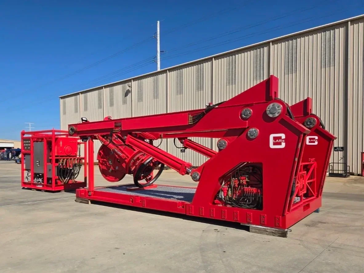 Large red industrial mechanical equipment or machinery outside a warehouse building on pavement.
