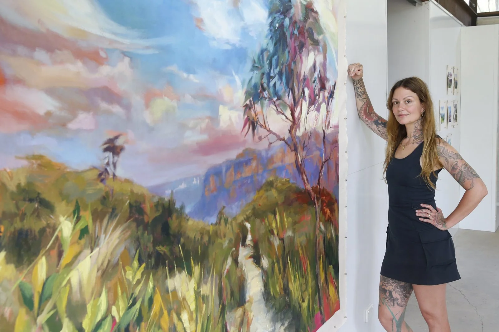Lacey Jane standing next to a large landscape painting.