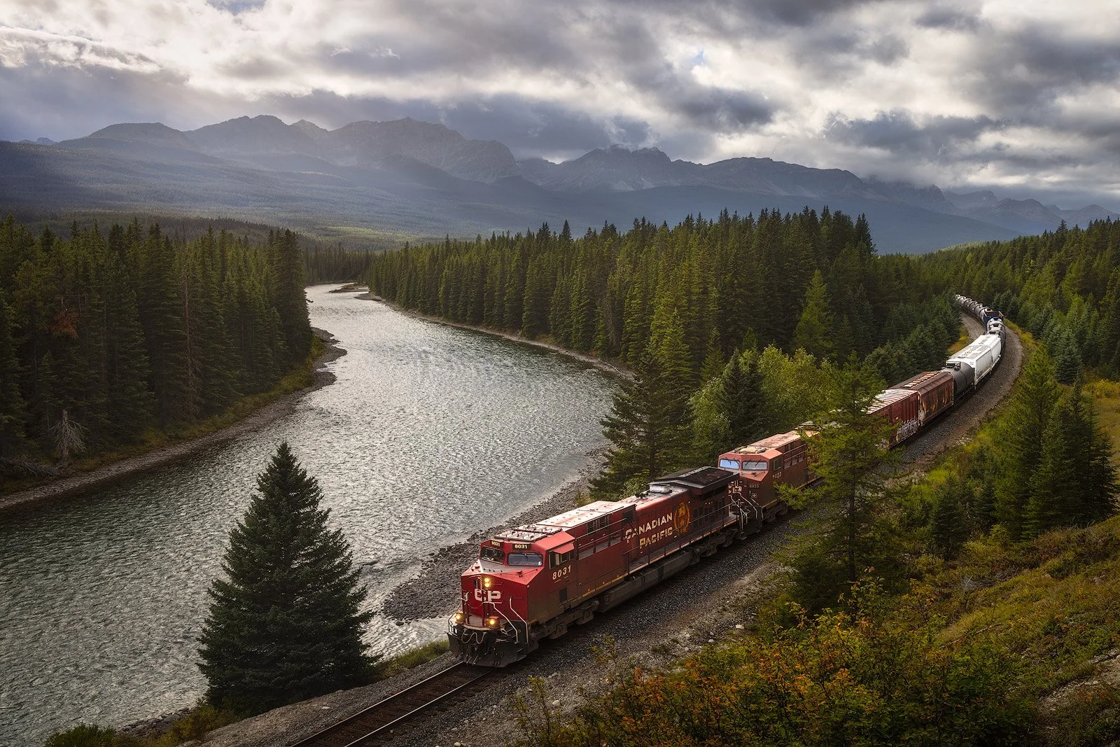 Canadian Pacific Train Winding Through Forested Valley Beneath Storm Mountain.jpg