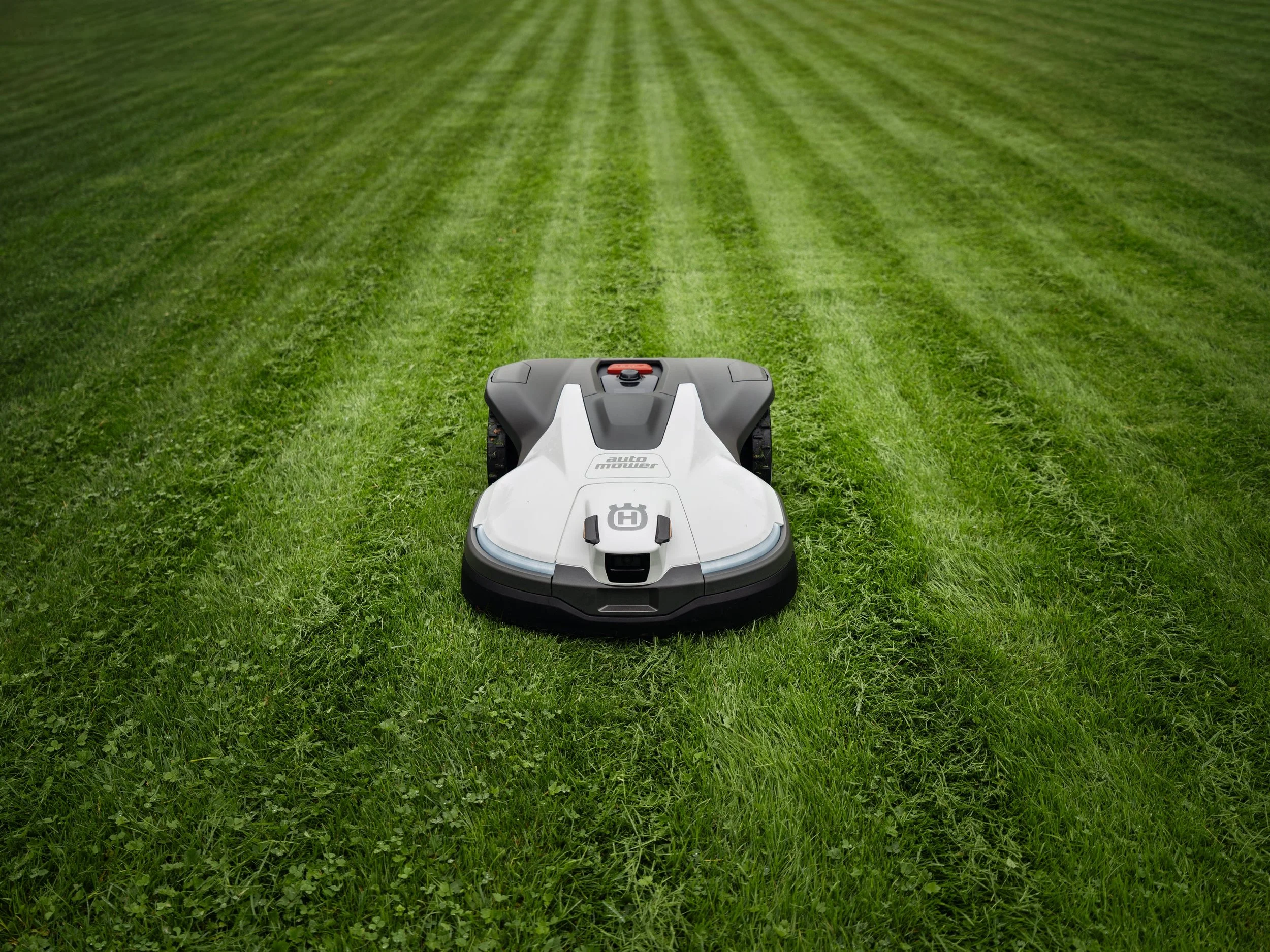 Autonomous robotic lawn mower on a freshly mowed grassy field.