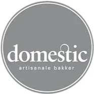 Een ronde, grijze achtergrond met witte tekst die zegt 'domestic artisanale bakker'.