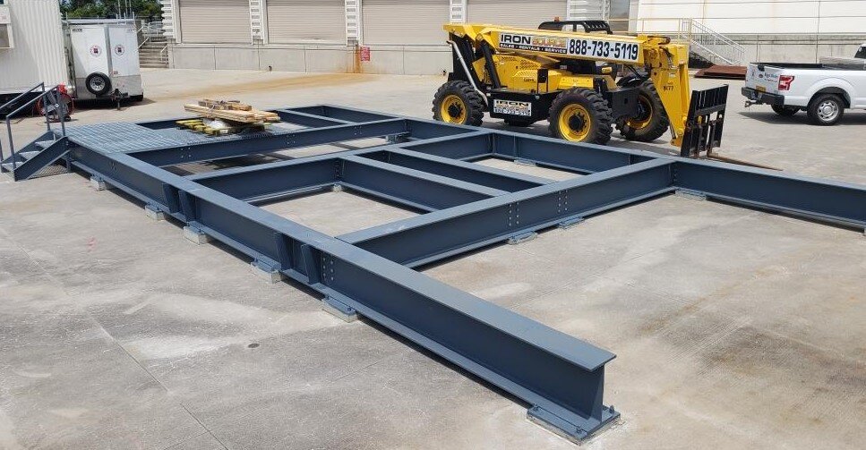 Steel frame structure on a concrete surface with forklift nearby.