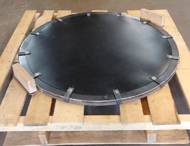 Round black metal object on a wooden pallet