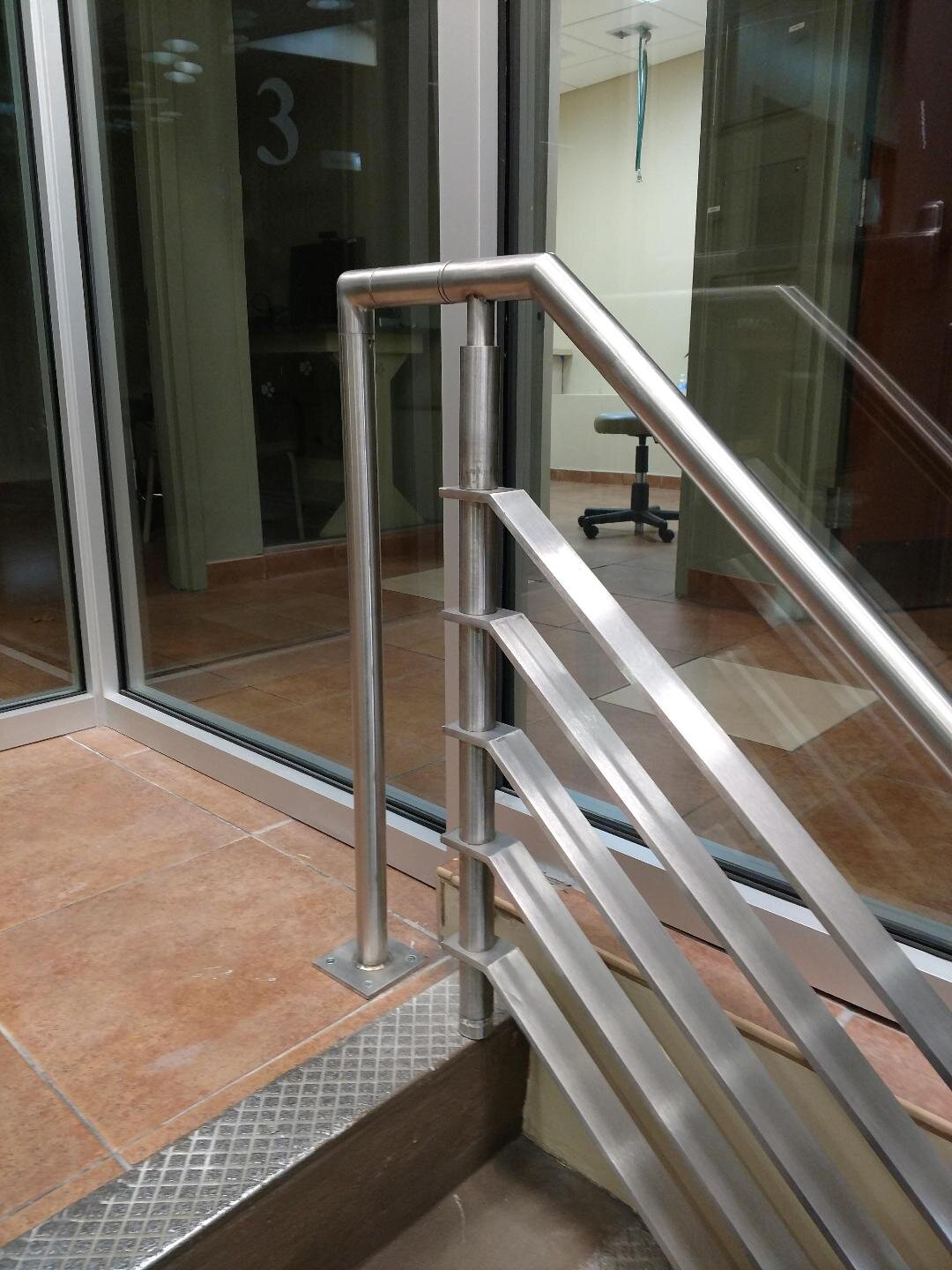 Stainless steel staircase railing near glass office doors and tiled floor