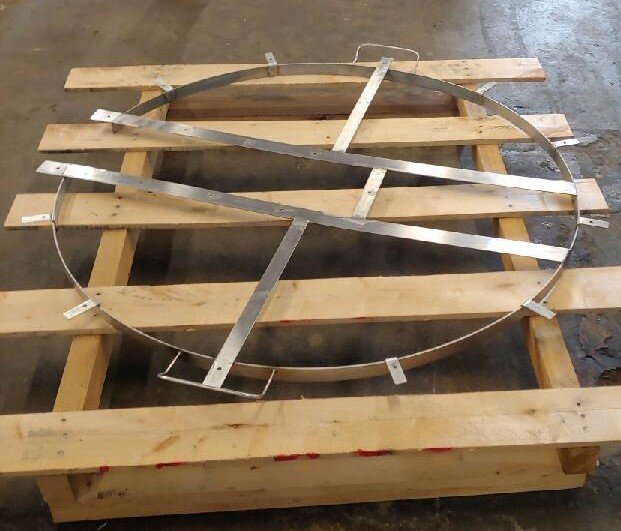 Metal circular frame with crossbars on a wooden pallet.