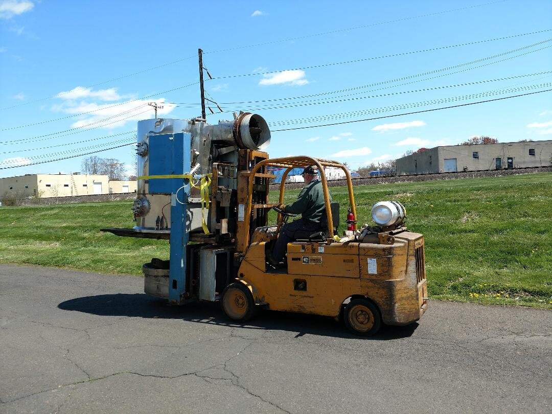 A forklift carrying industrial equipment outdoors