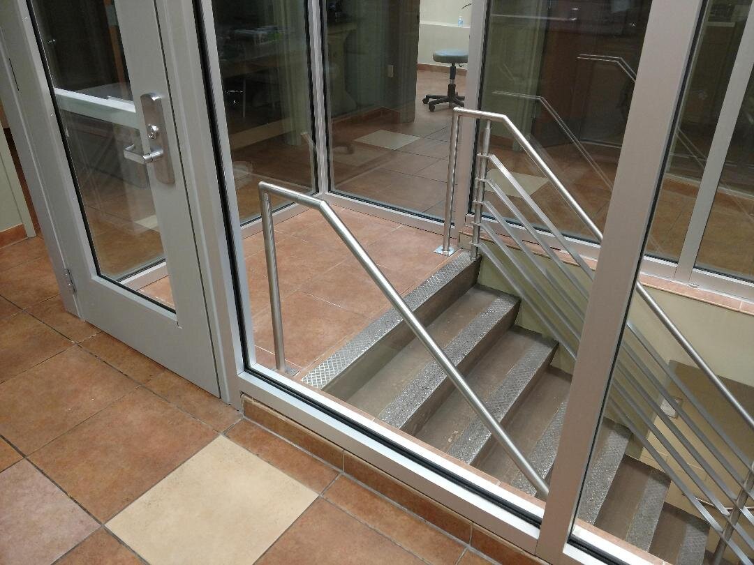 Glass doors and windows enclosing a staircase with metal railings on a tiled floor.