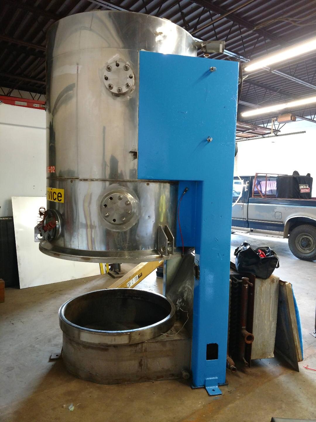 Industrial metal machinery with a blue component in a workshop setting.