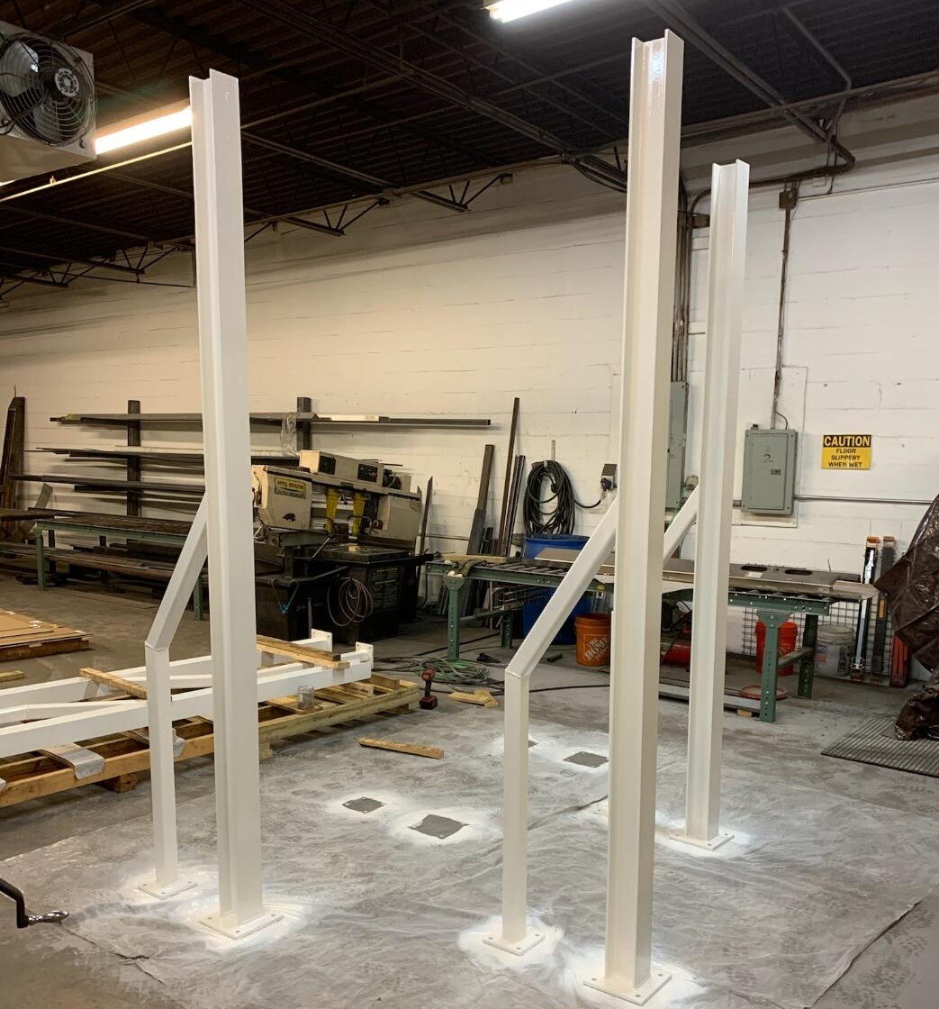 Metal beams in a workshop with tools and equipment in the background.