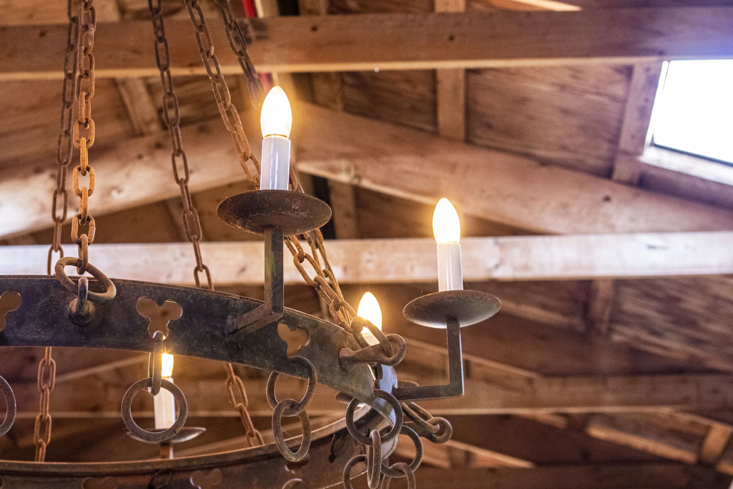 Rustic chandelier with lit bulbs hanging from wooden ceiling