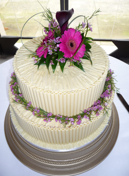 White chocolate cigarello cake with pink gerberas.PNG