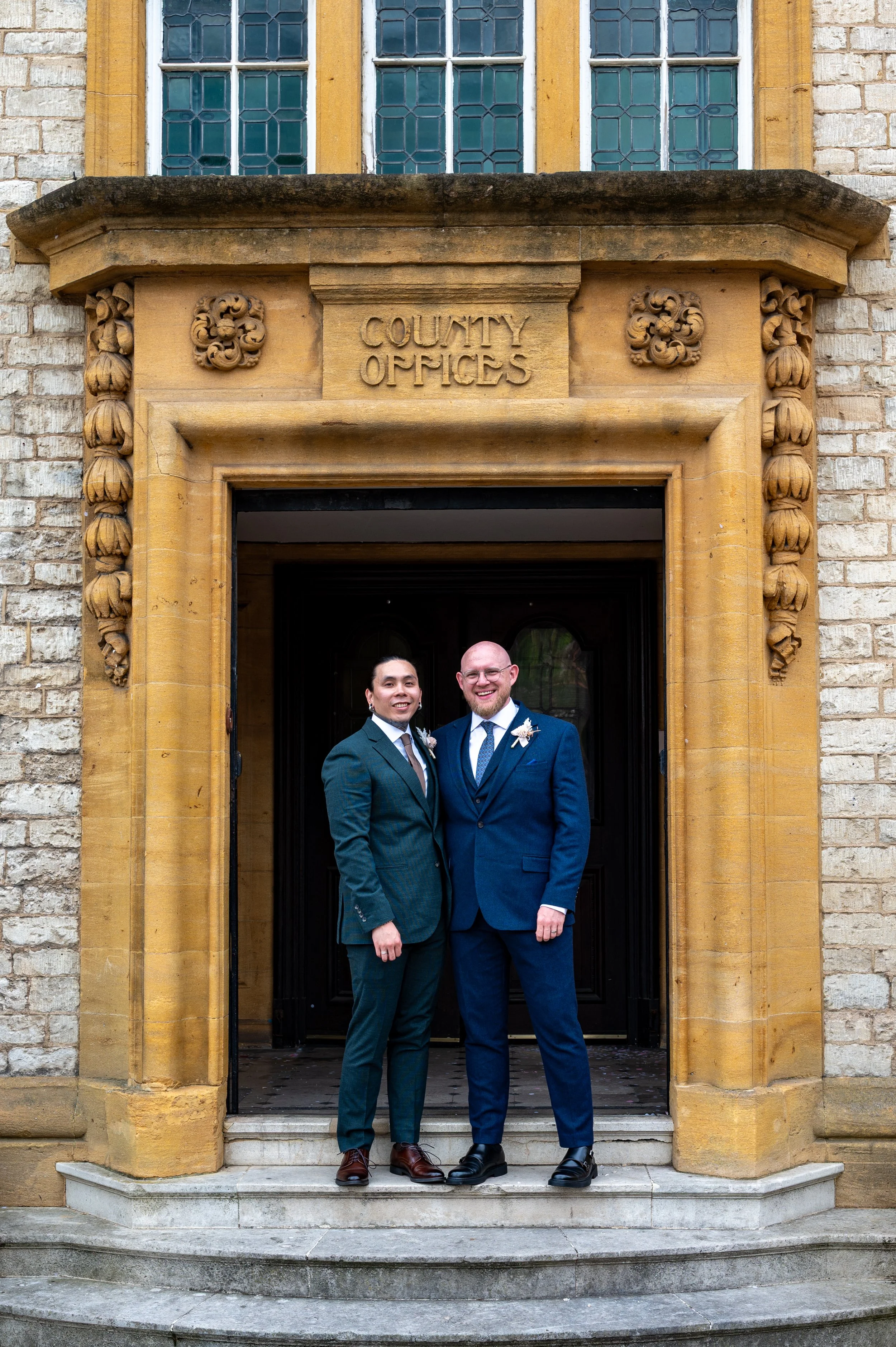 Two Grooms stand outside The Dexter Rooms in Oxford after their marriage