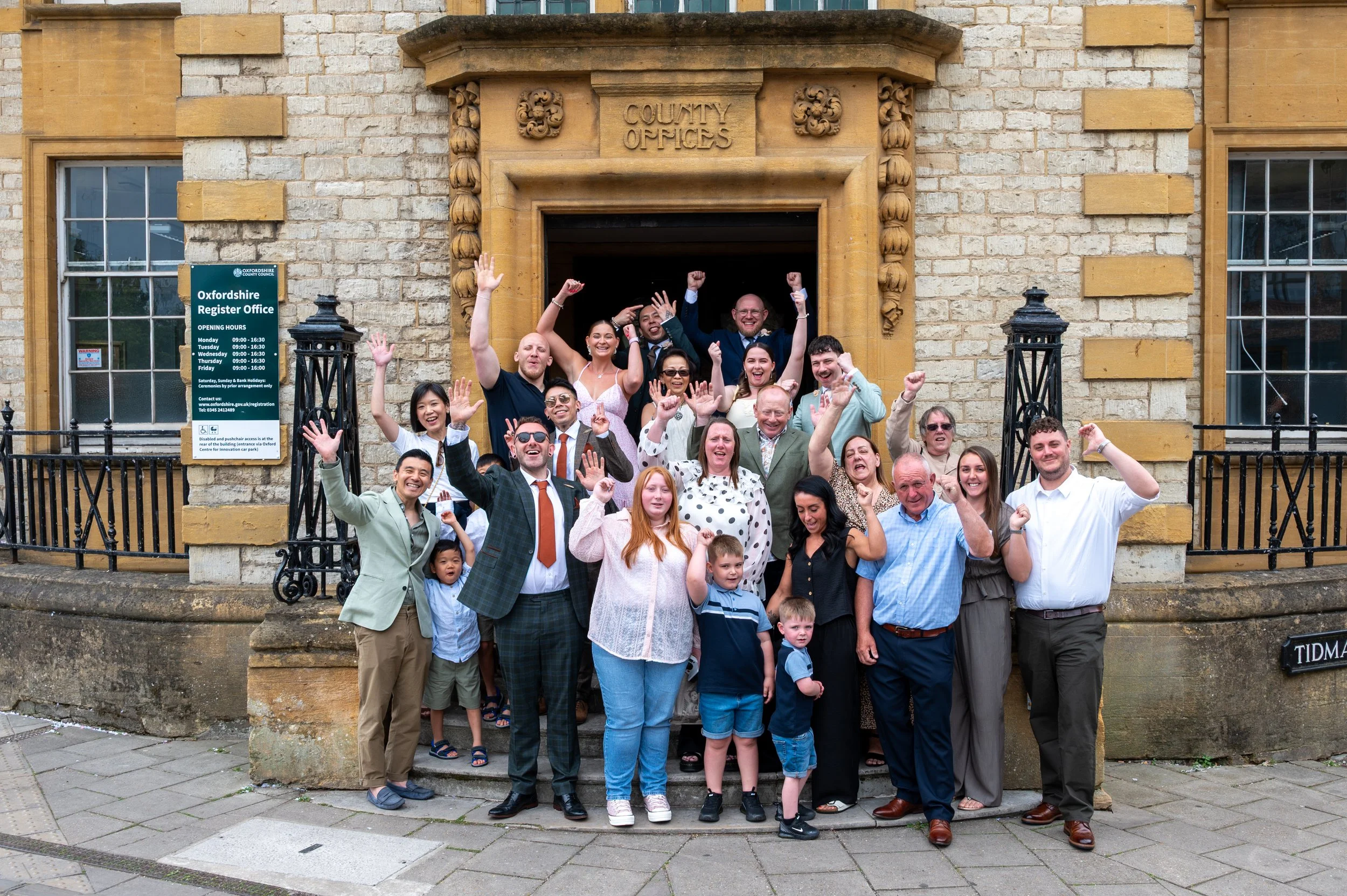 Wedding guests pose and wave during their photos outside The Oxford Registry Office