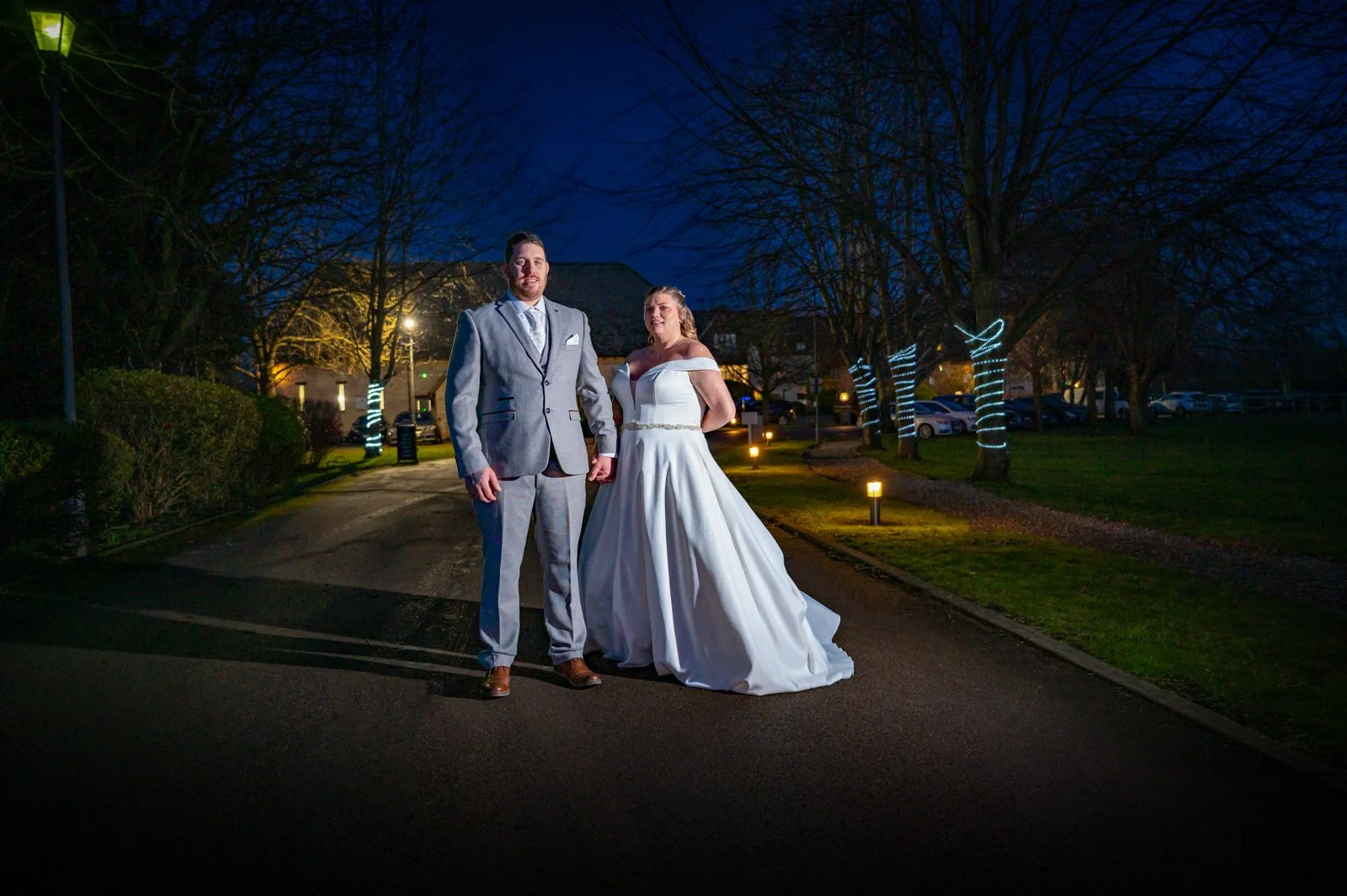 A newly married couple stand at the entrance to Voco Spires during dusk