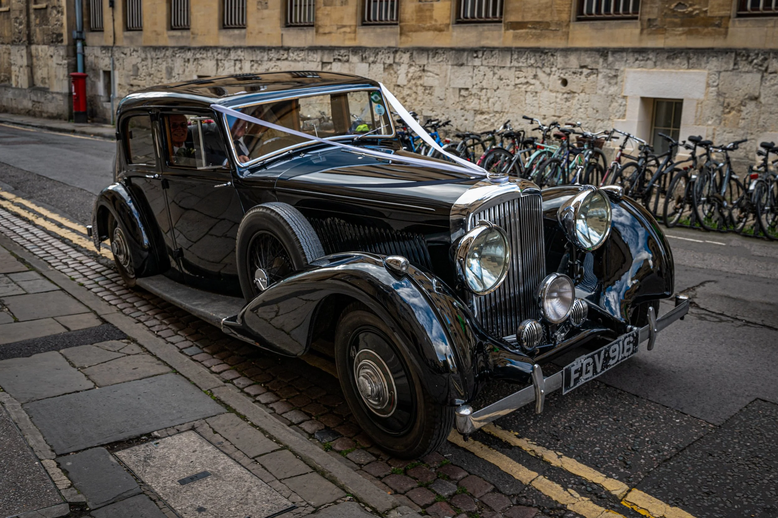 an old vintage car with white ribbons on it arrives with a bride at her wedding