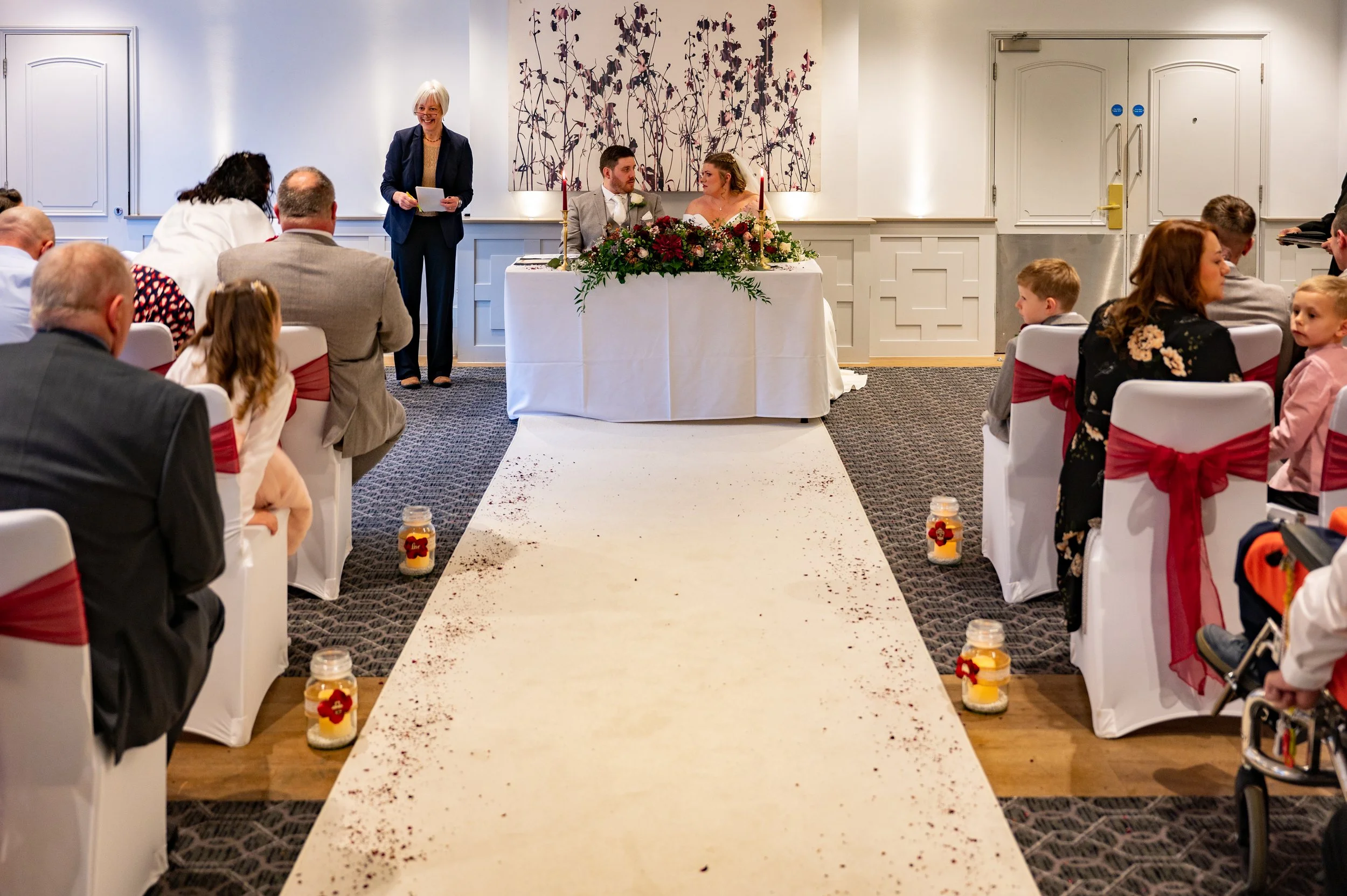 A bride and groom sit at a table in front of their guests