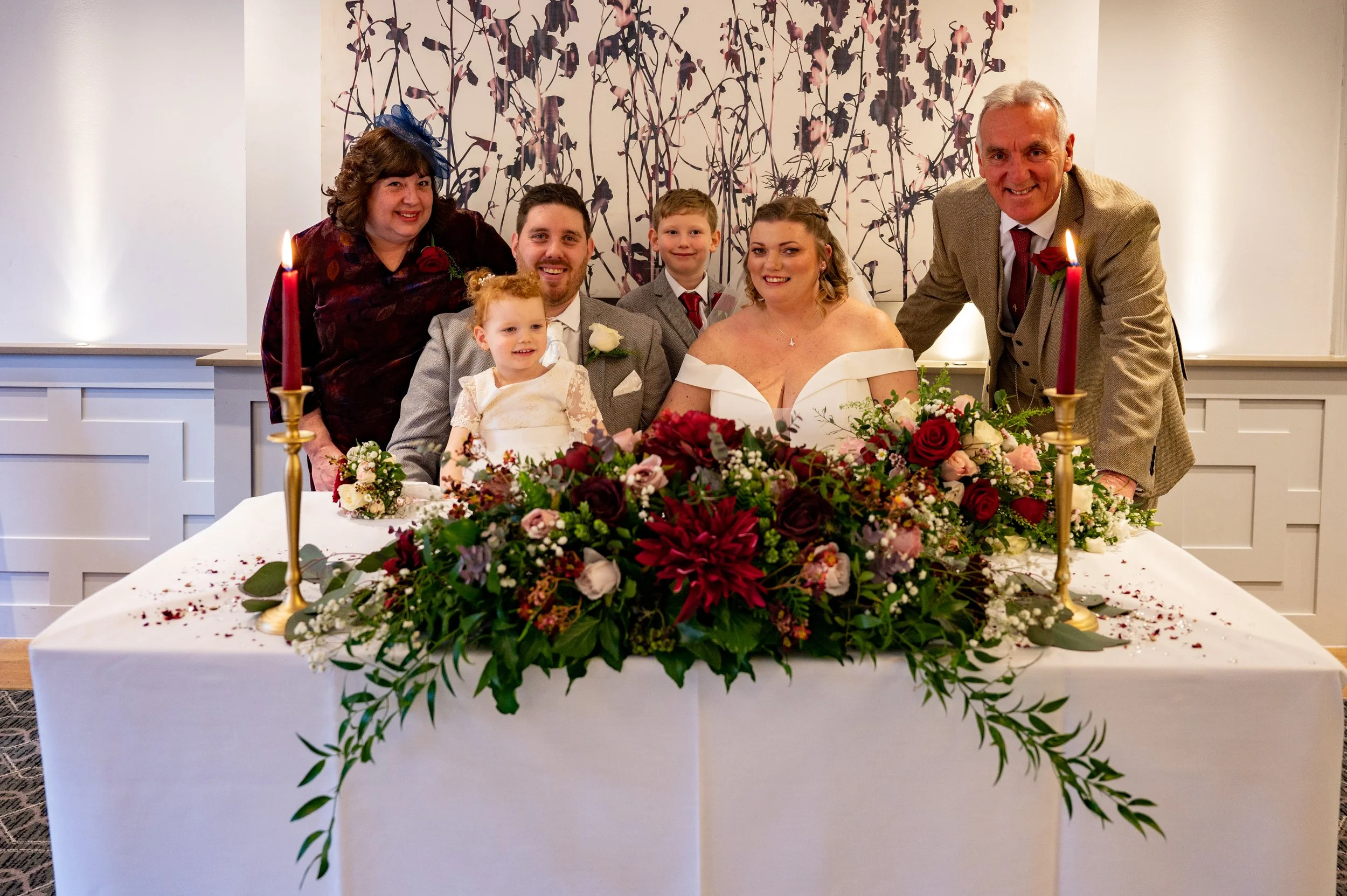The bride and groom sit at a table surrounded by wedding witnesses