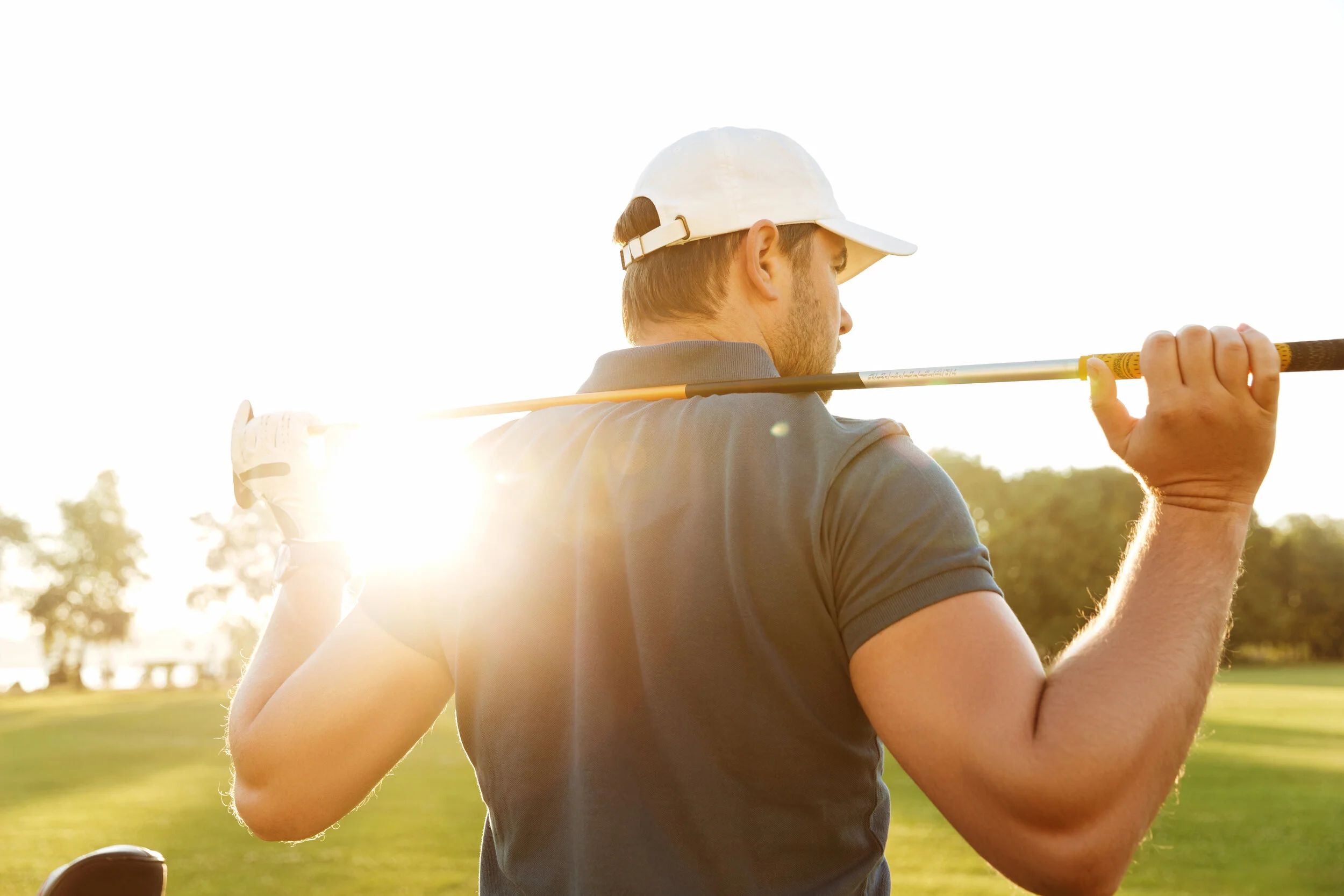 back-view-of-a-young-man-carrying-golf-club-while-standing-on-field-SBI-321518482.jpg