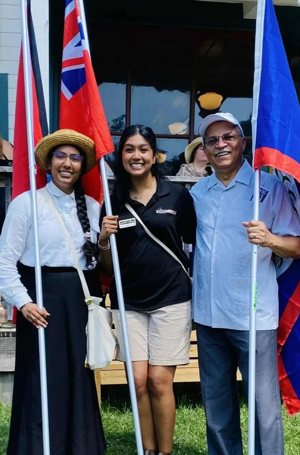 A photo of three people smiling and holding large flags.