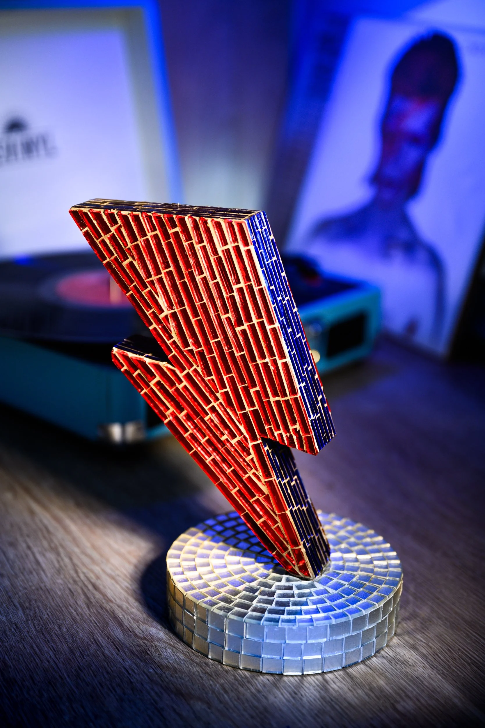 Glass mosaic sculpture

A hand-cut glass mosaic lightning bolt inspired by Bowie’s iconic flash. Built from red and blue tesserae and set into a mirrored base, the piece plays with light, reflection, and tension. It’s bold, physical, and unapologetic