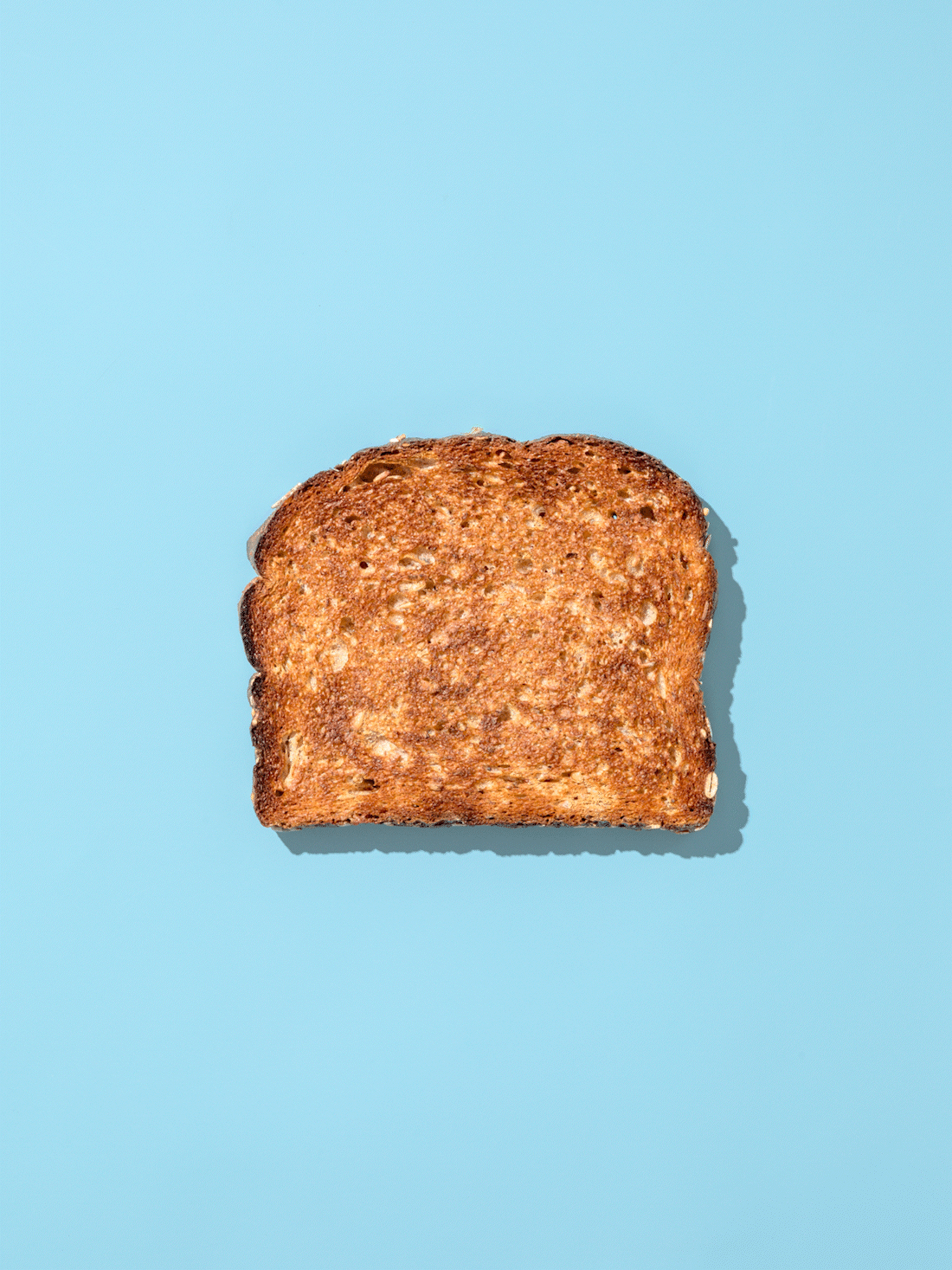 Stop motion of a piece of wheat toast transforming between being cut diagonally and vertically down the middle on a light blue background.