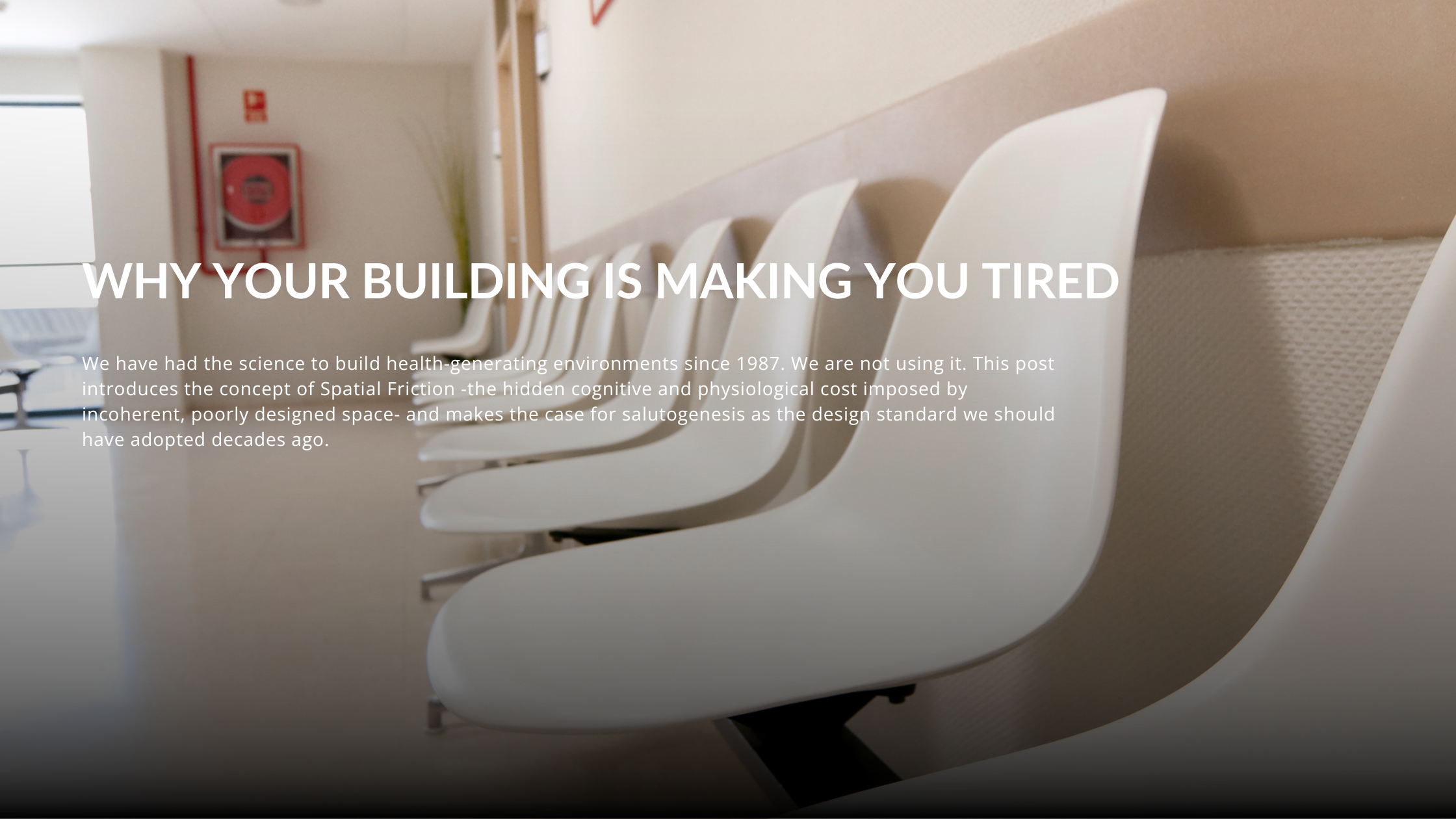 Empty row of identical white plastic chairs in a clinical waiting room, photographed from a low angle along a pale featureless wall, with a fire extinguisher sign and a partially visible corridor in the background.
