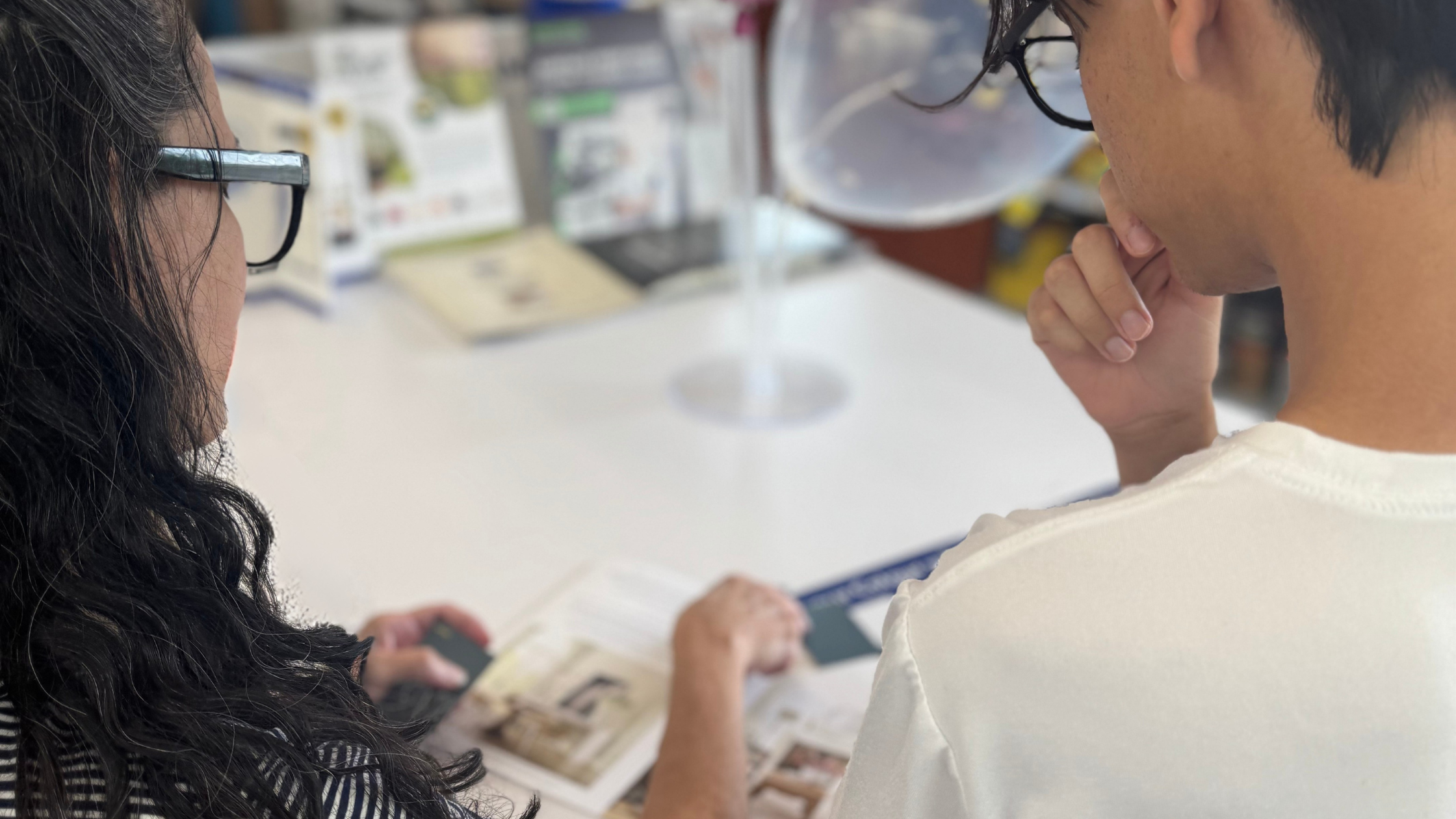 Over-the-shoulder view of interior designer reviewing paint swatches and colour samples with a client at a design counter.