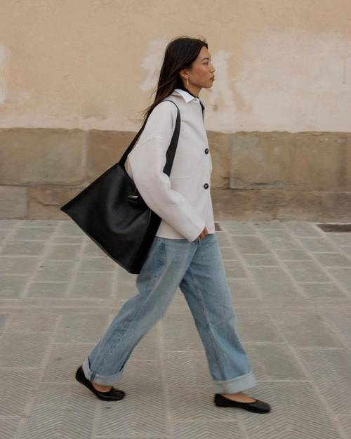 Look casual com jeans, sabrinas pretas e mala oversized na rua..png