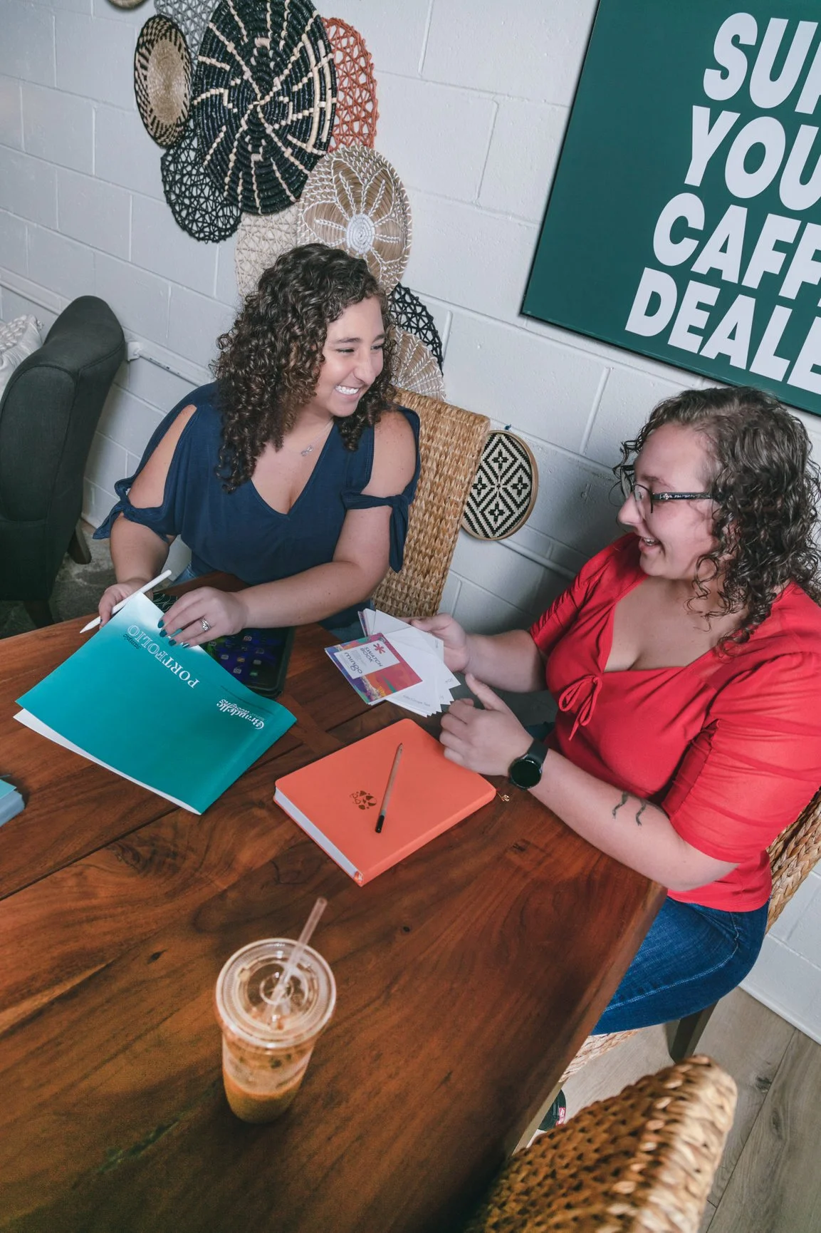 Brandelle Design Team of two women seated at a wooden table in coffee shop in Denver, NC having a design meeting together