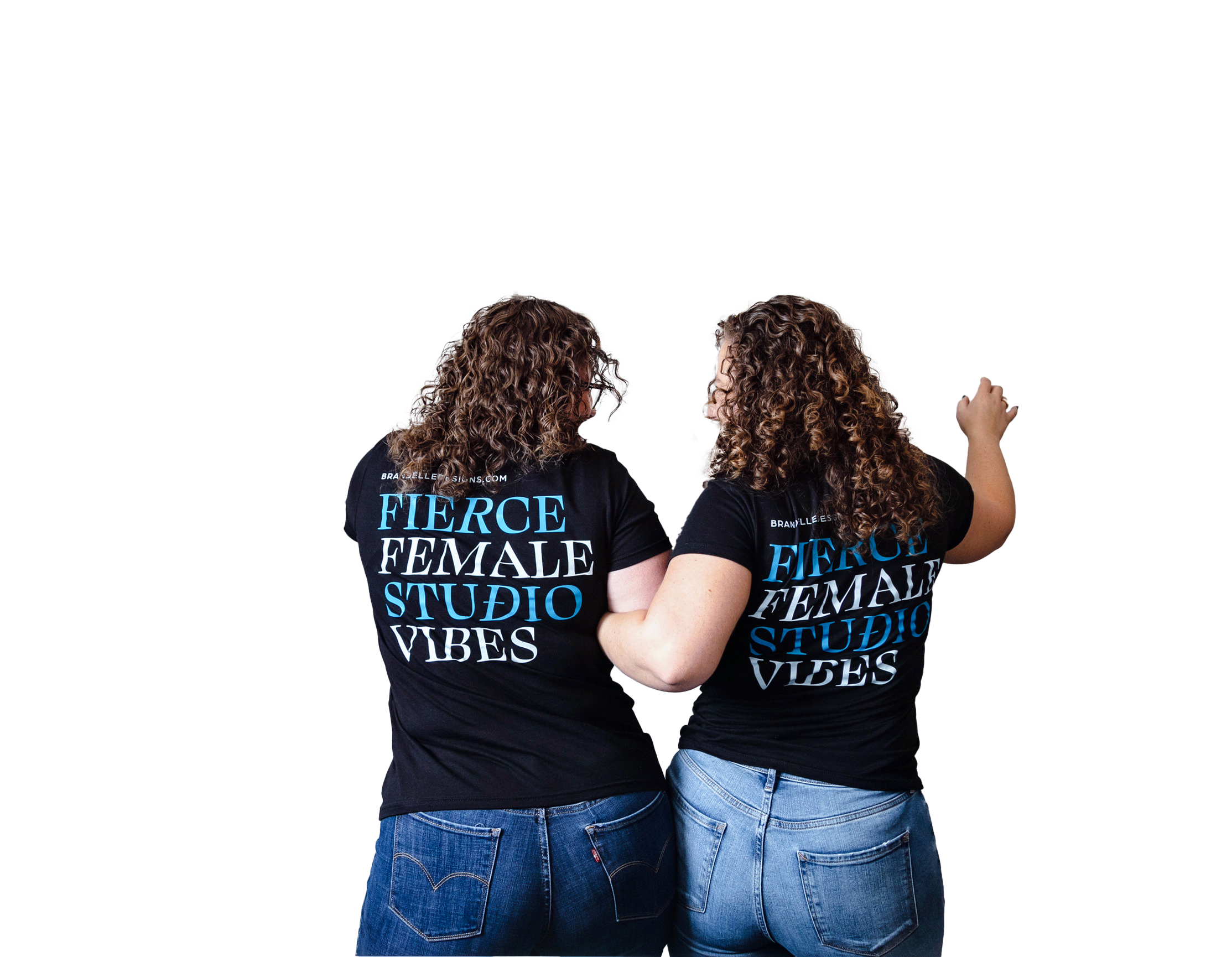 Two women with curly hair wearing black T-shirts that read 'FIERCE FEMALE STUDIOS VIBES' standing close together, facing each other, with one woman's arm around the other's shoulder, in front of a plain background.