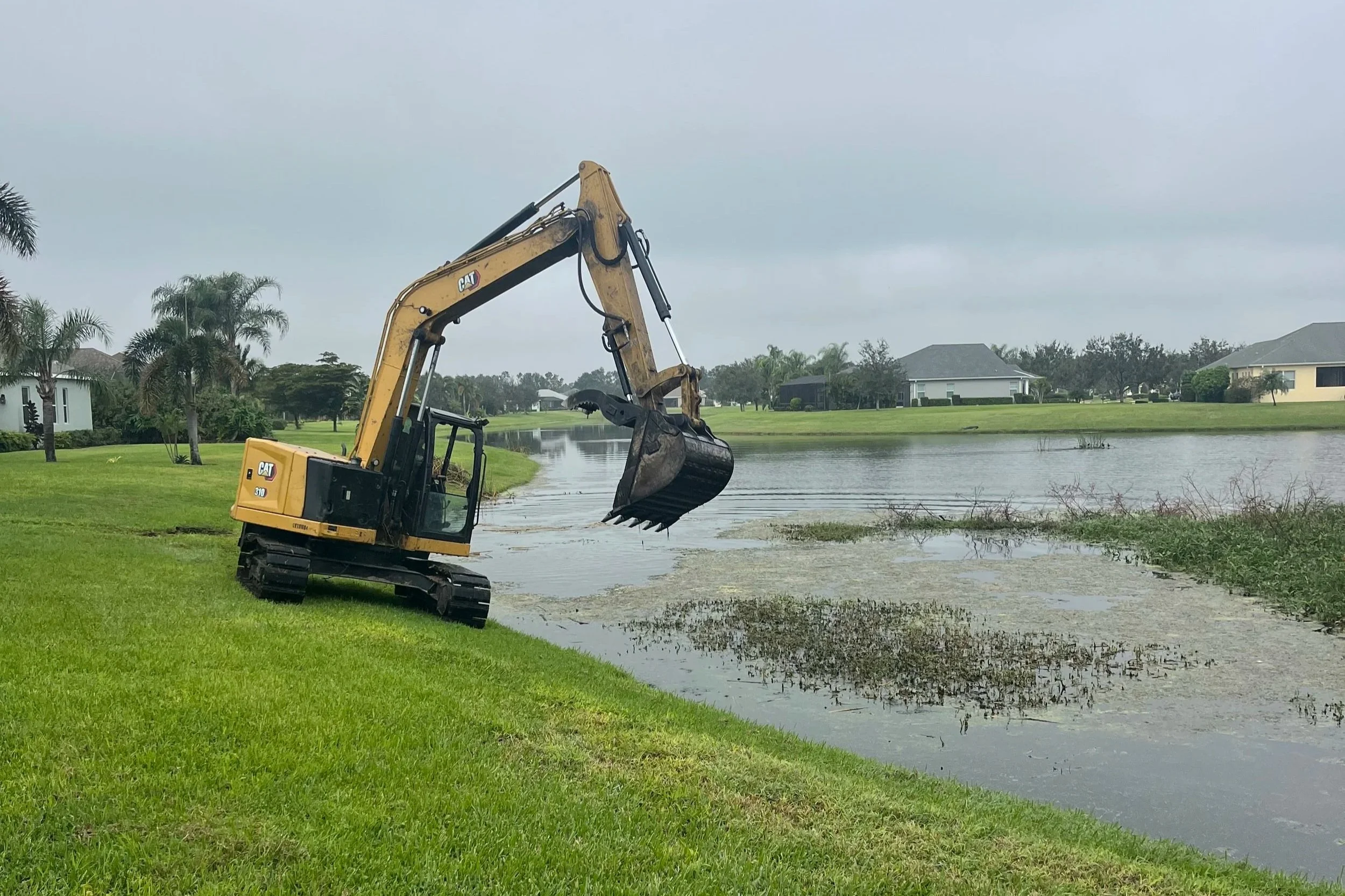 Excavator demucking in a residential retention pond