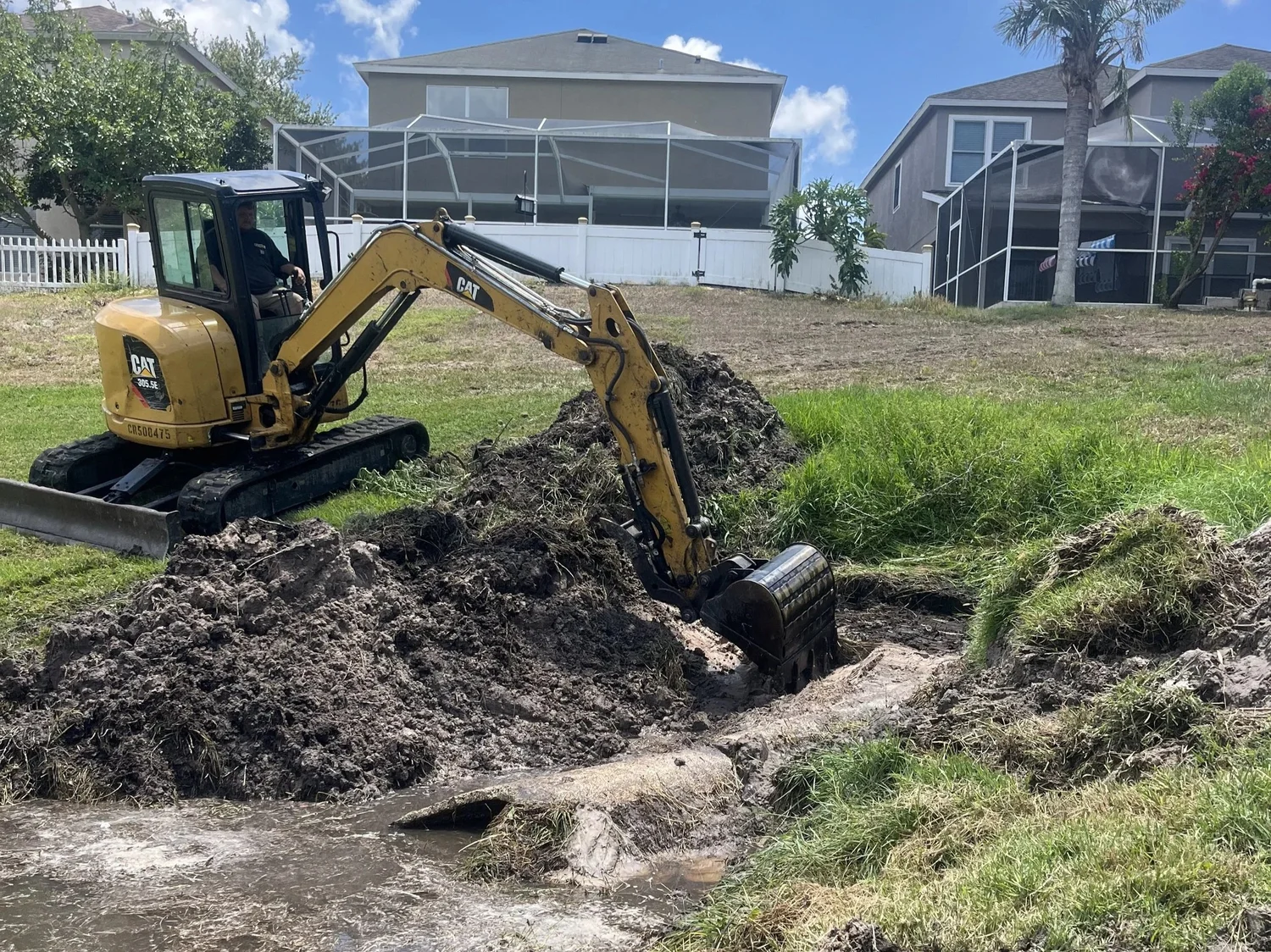 Excavator grading a drainage ditch