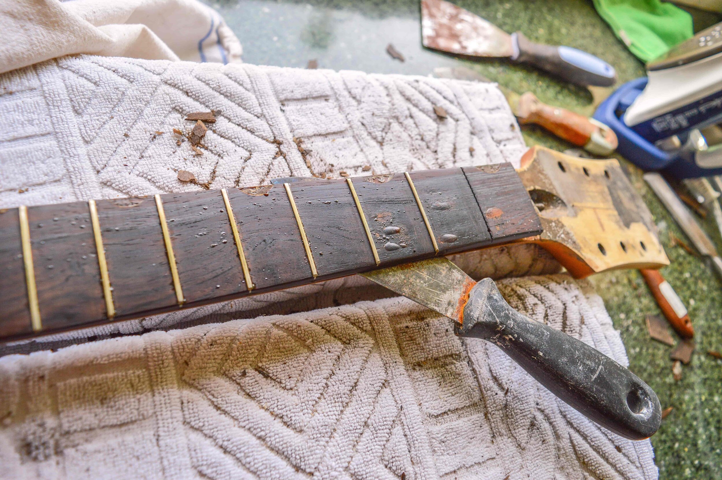 A hot clothes iron, some palette knives and a lot of patience and care are needed to seperate the fretboard from the neck.