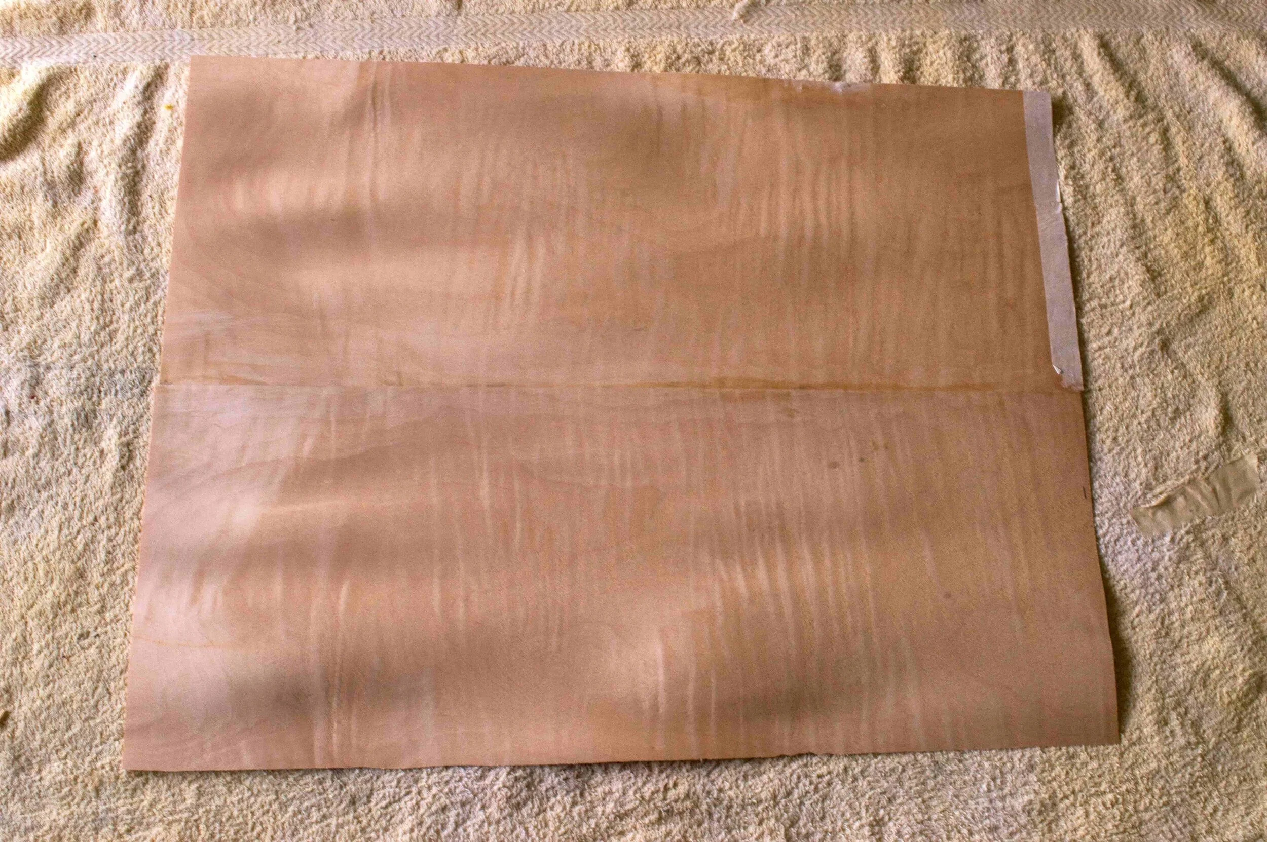 Bookmatched sheets of curly maple veneer are glued together before fixing onto the body.