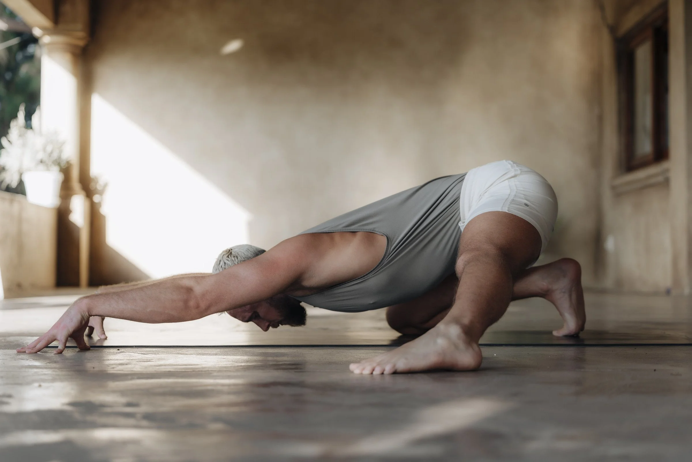 Tom reaching forward in a seated floor stretch during a movement practice.