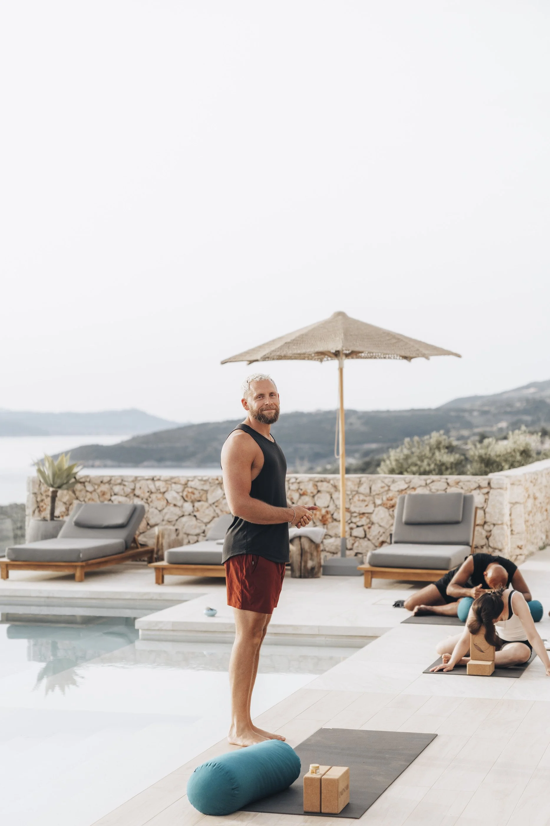 Tom teaching a small outdoor movement session beside a pool on retreat.
