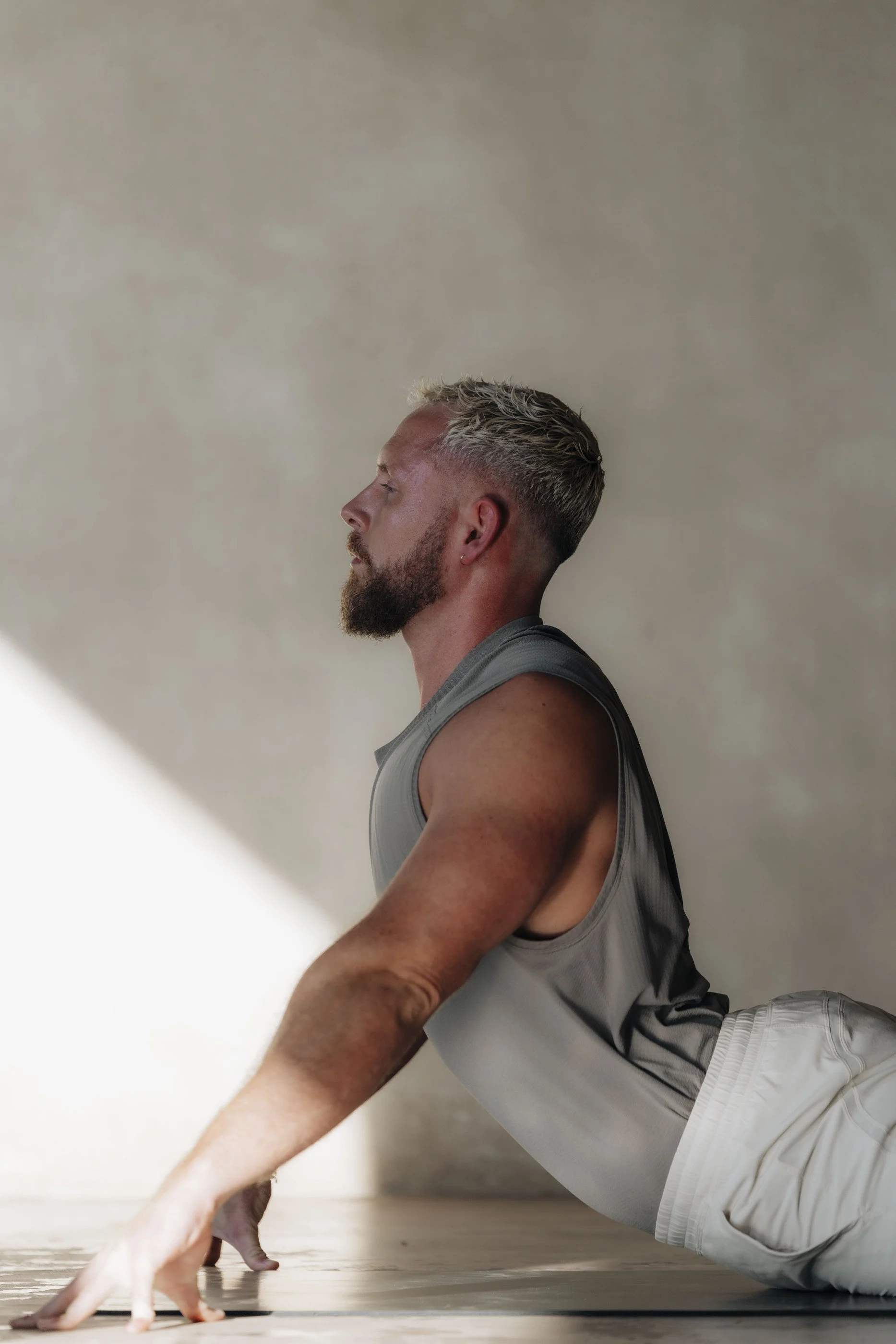 Tom practising a floor-based backbend in soft studio light.