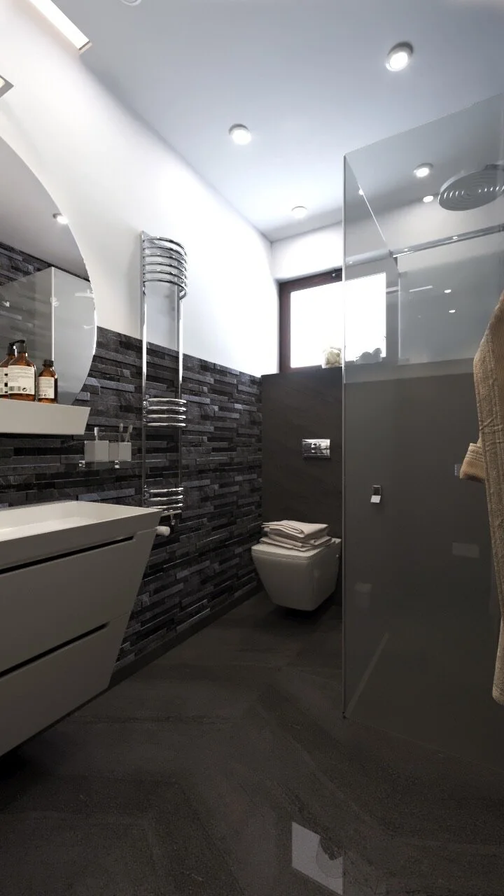 Modern bathroom with black textured wall tiles, white vanity, round mirror, small window with natural light, toilet with folded towels on top, glass shower partition, and a towel hanging on the side.