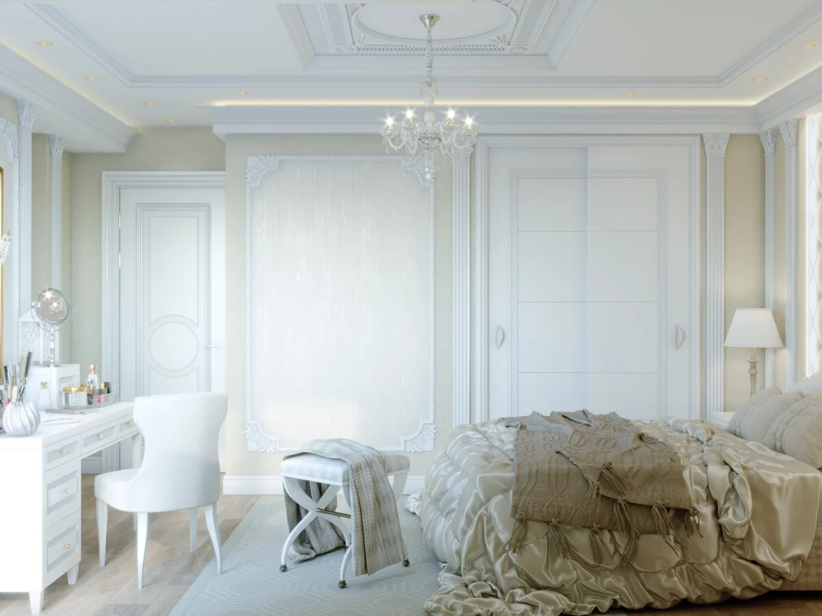 Elegant bedroom with a white bed, chandelier, vanity with mirror, armchair, and floor lamp, all in a neutral color palette.
