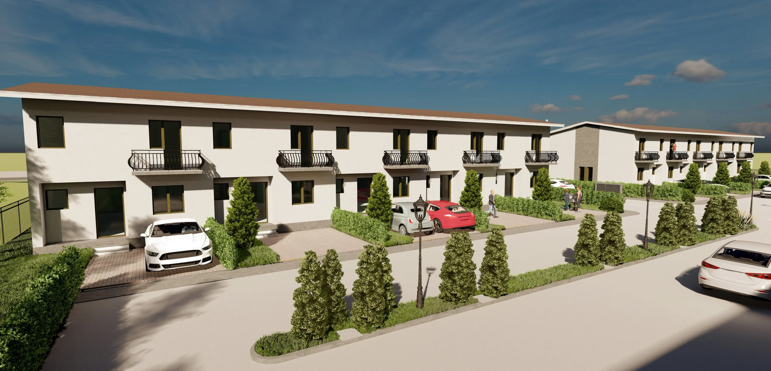 A modern white apartment complex with multiple two-story units, each with small balconies, surrounded by green bushes and small trees. Cars are parked in front, and People are walking near the buildings under a blue sky with scattered clouds.