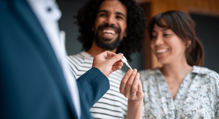 Happy homebuyers receiving house keys from a real estate agent during a property closing, representing successful home purchase, real estate transactions, and the homeownership journey.